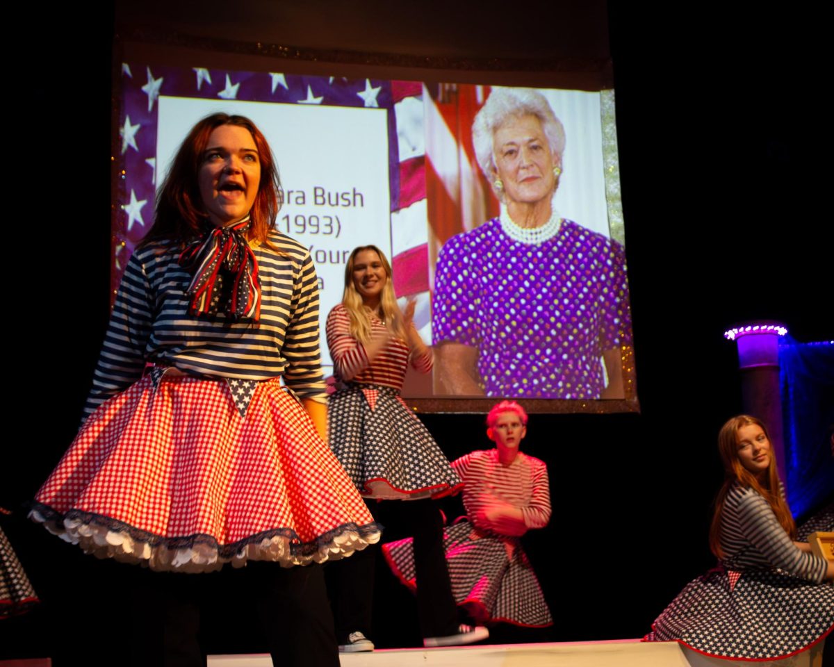 Bryn Mongeau performing with actors Lillian Guggisberg, Eden Riegle and Arianna Urch behind her.